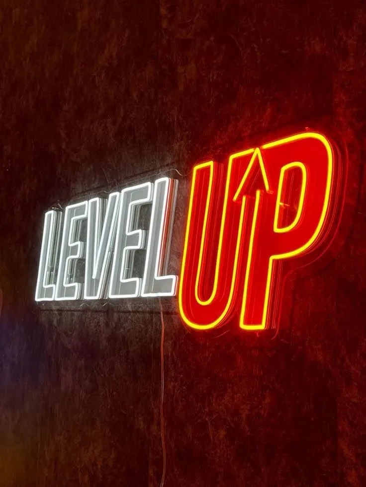 Opplyst LED-neonskilt «LEVEL UP» i hvitt og rødt på en vegg